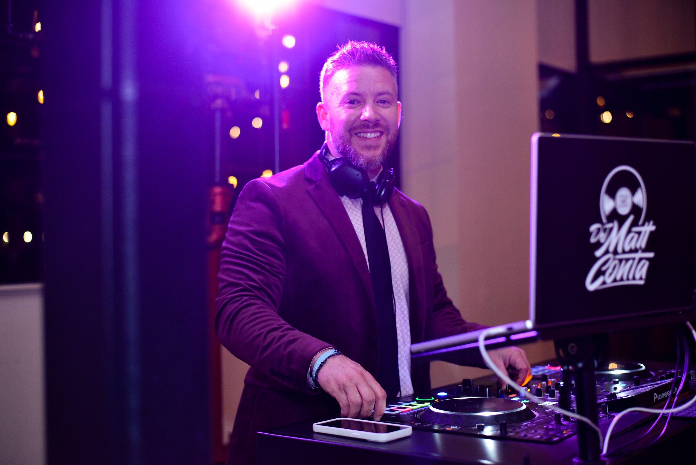 DJ Matt Conta smiling as he works the DJ controller under purple lighting